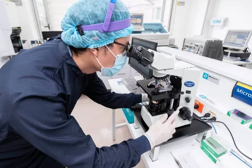 Profesional de laboratorio clínico analizando muestras con microscopio en la Clínica Universitaria Colombia